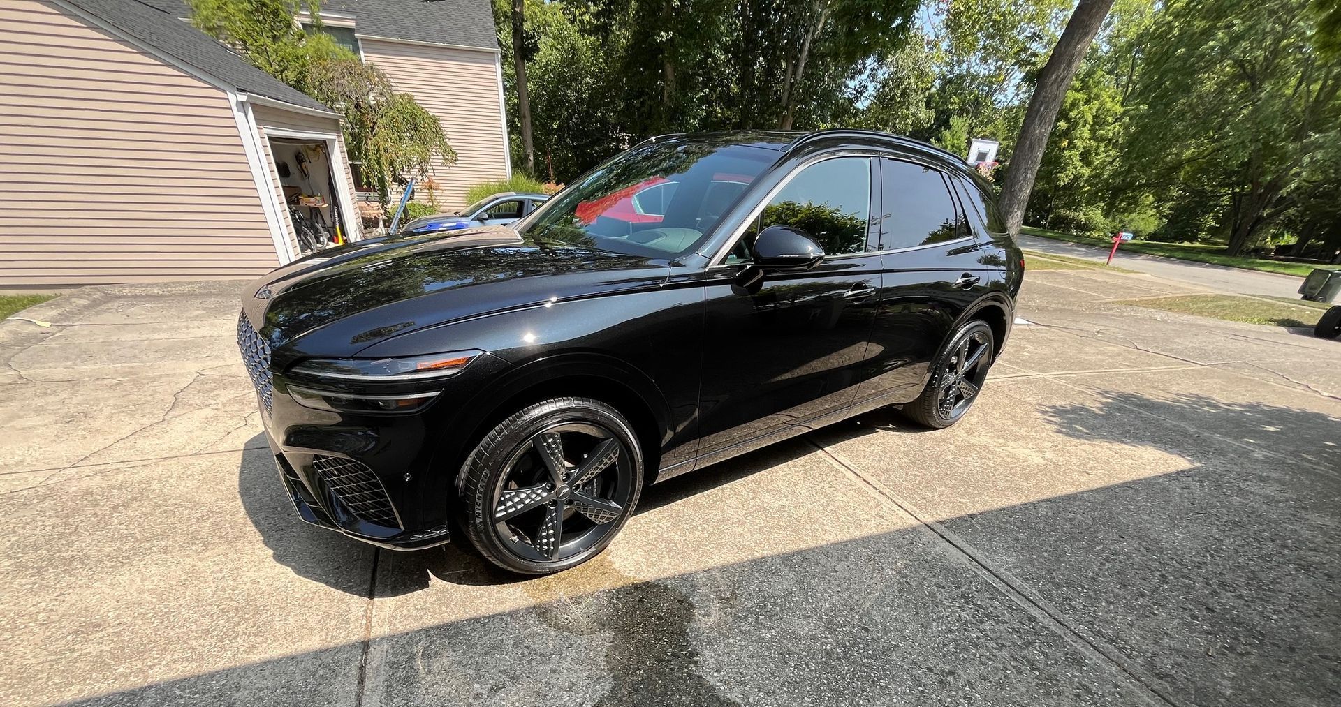 A black car is parked in a driveway in front of a house.