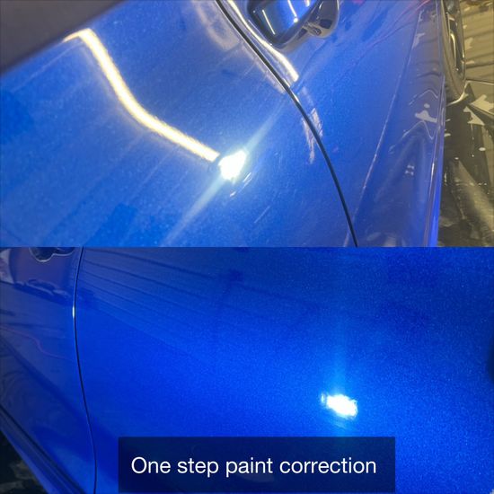 Blue car body panel showing glossy one-step paint correction under bright shop lights