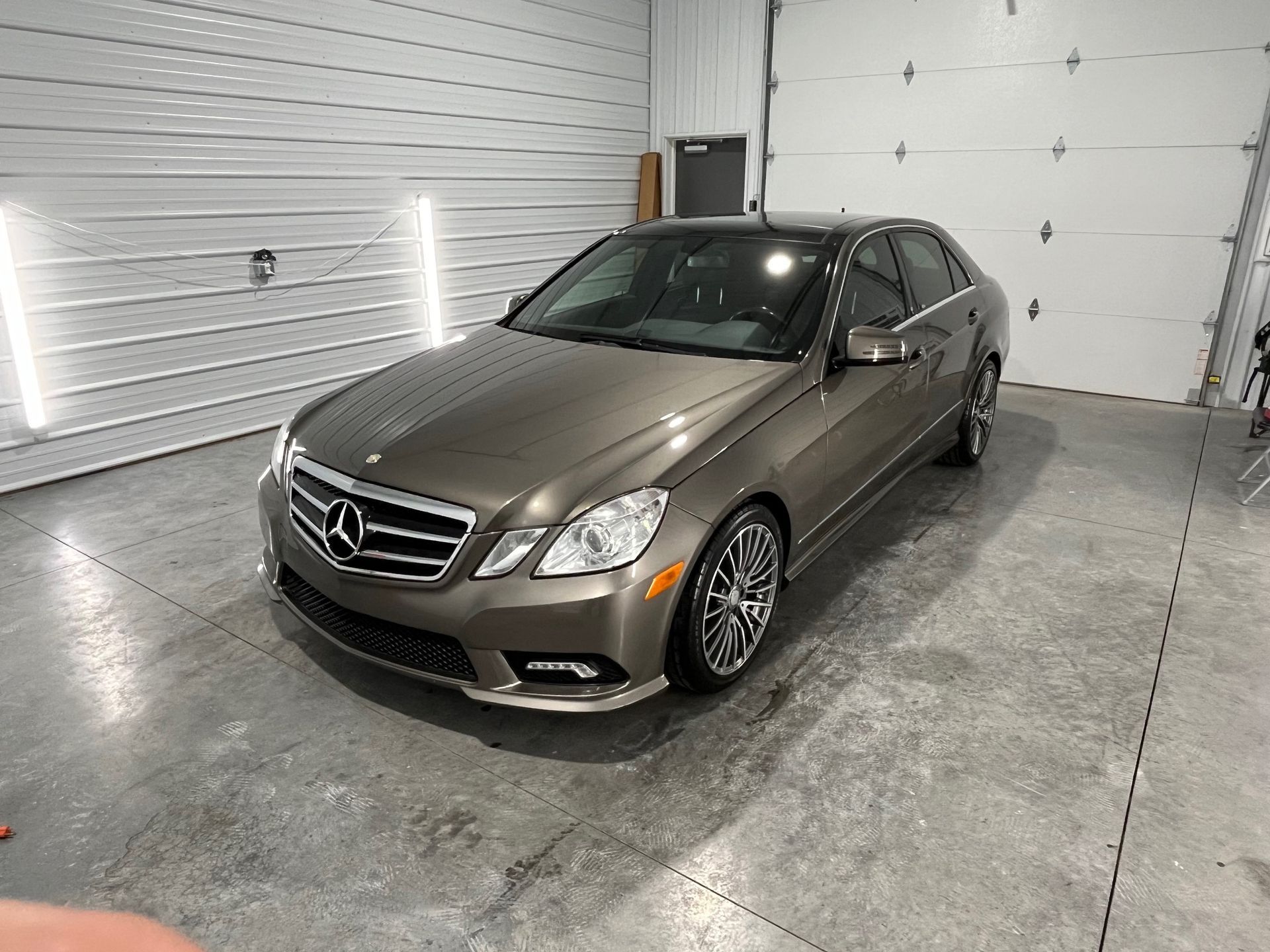 A mercedes benz is parked in a garage next to a garage door.