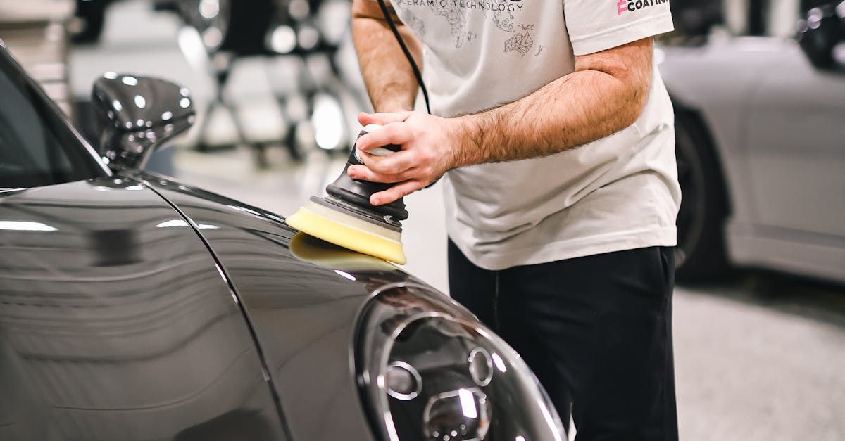 A man is polishing a car with a brush in a garage.