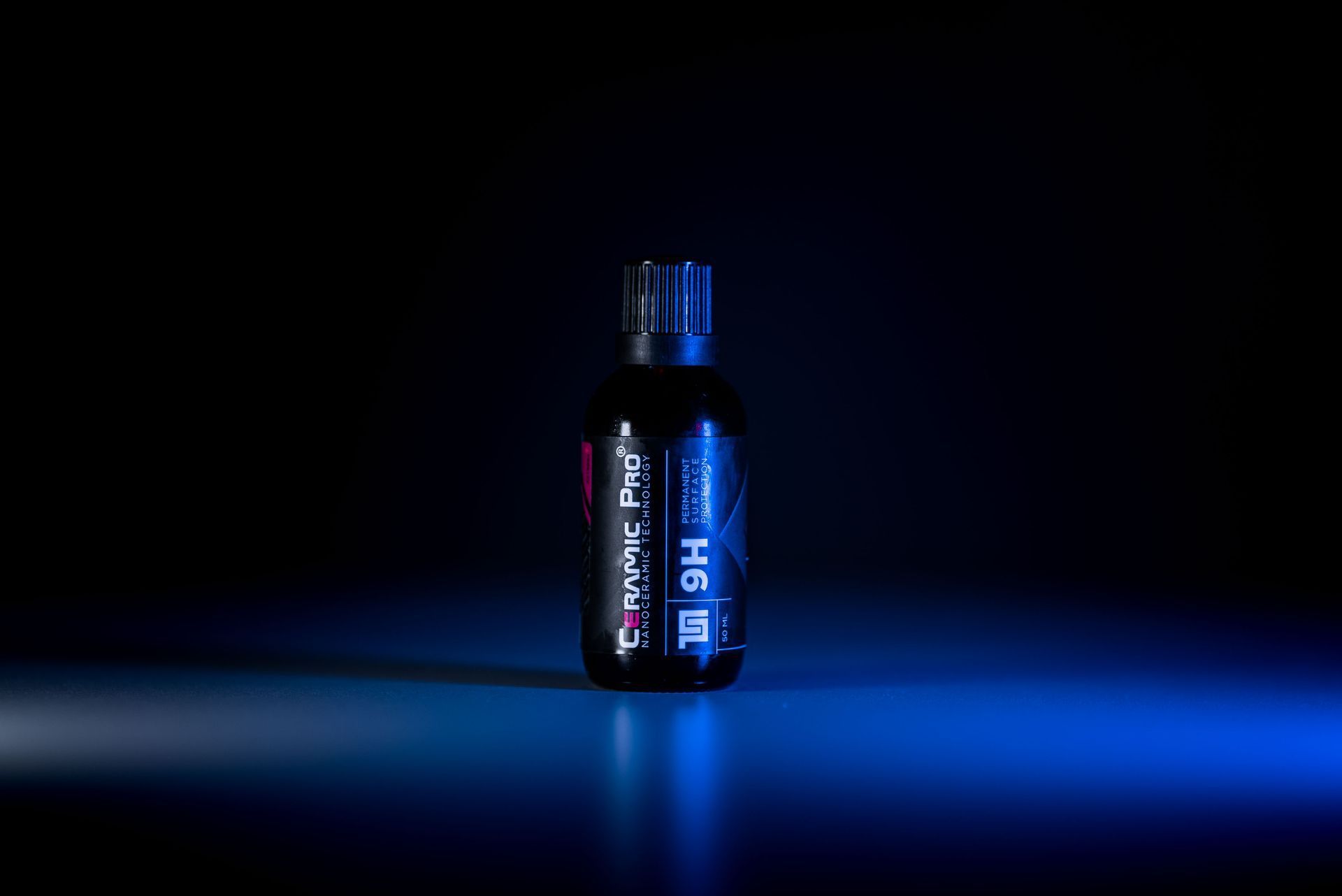 A bottle of liquid is sitting on top of a blue table.