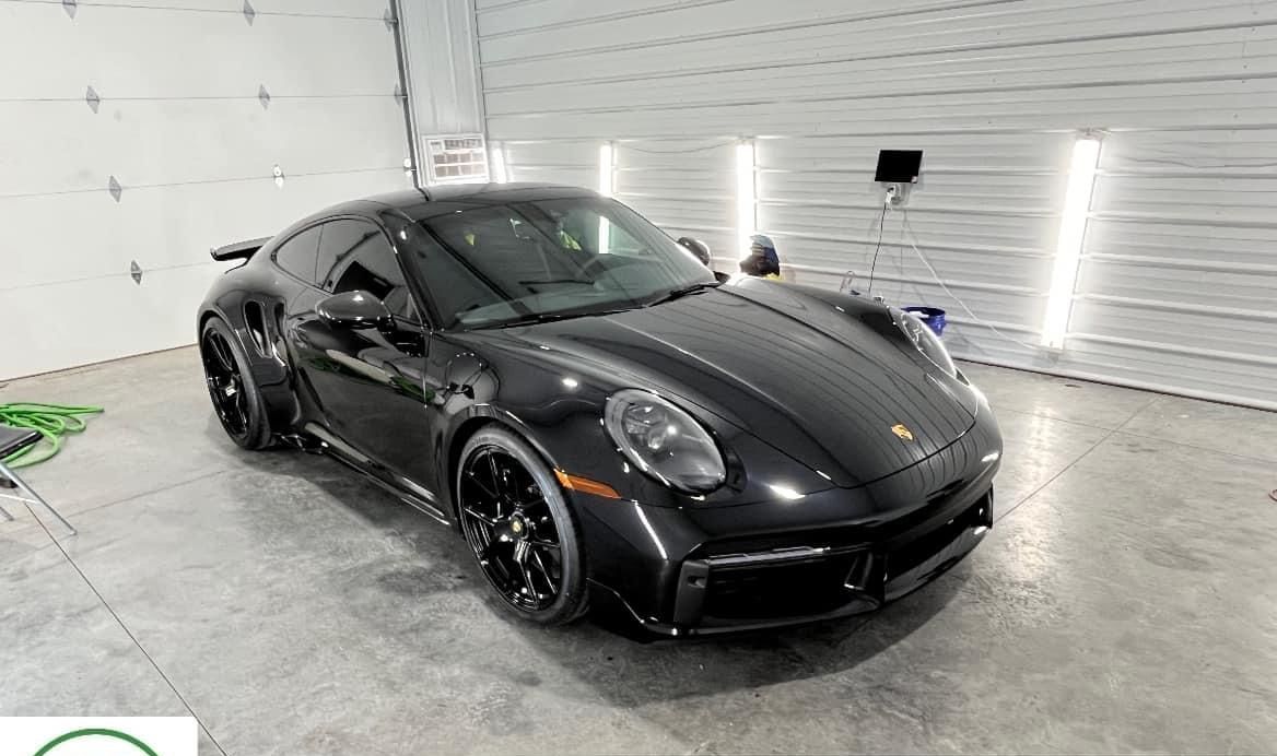 A black porsche 911 turbo s is parked in a garage.