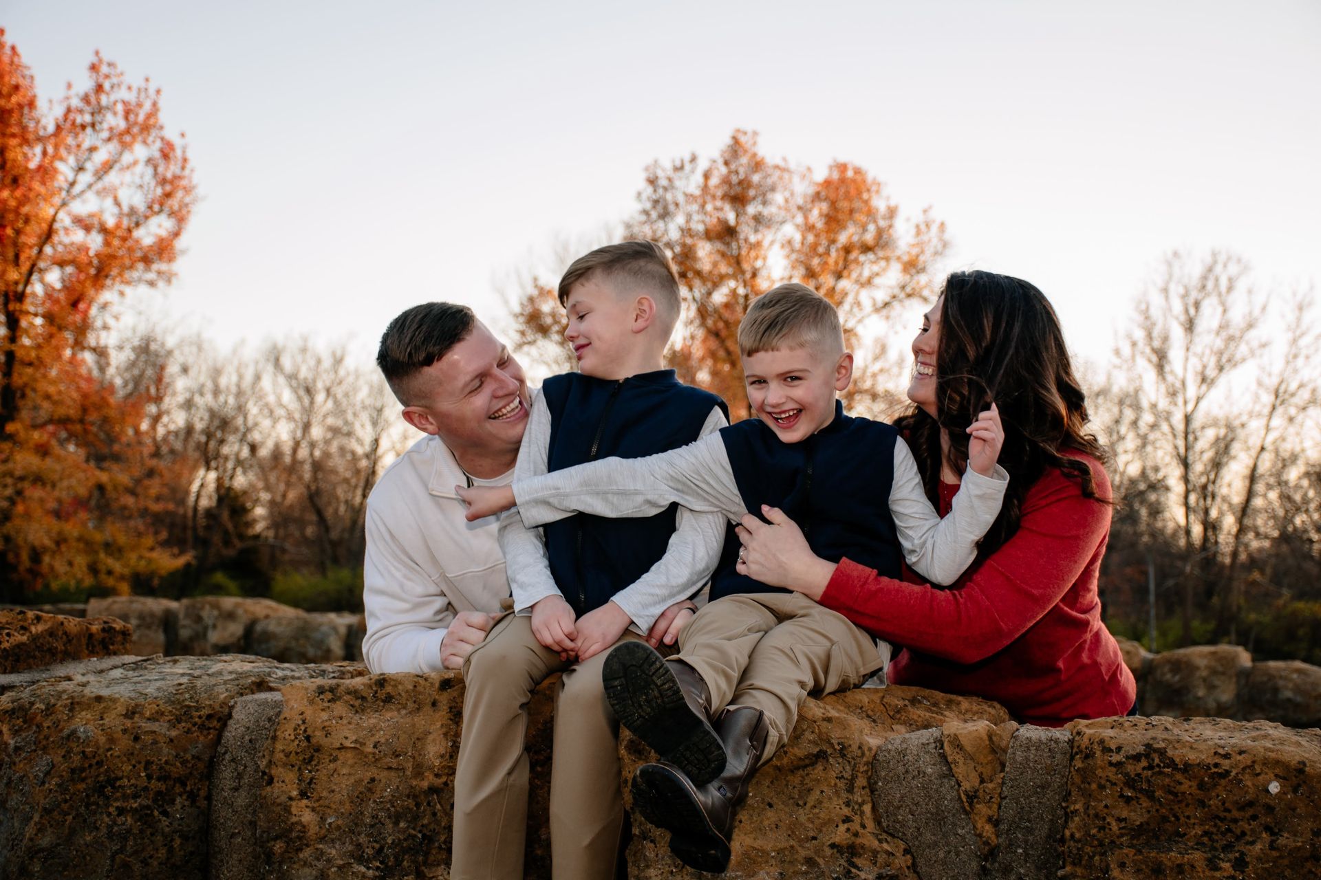 A family is sitting on top of a hay bale.