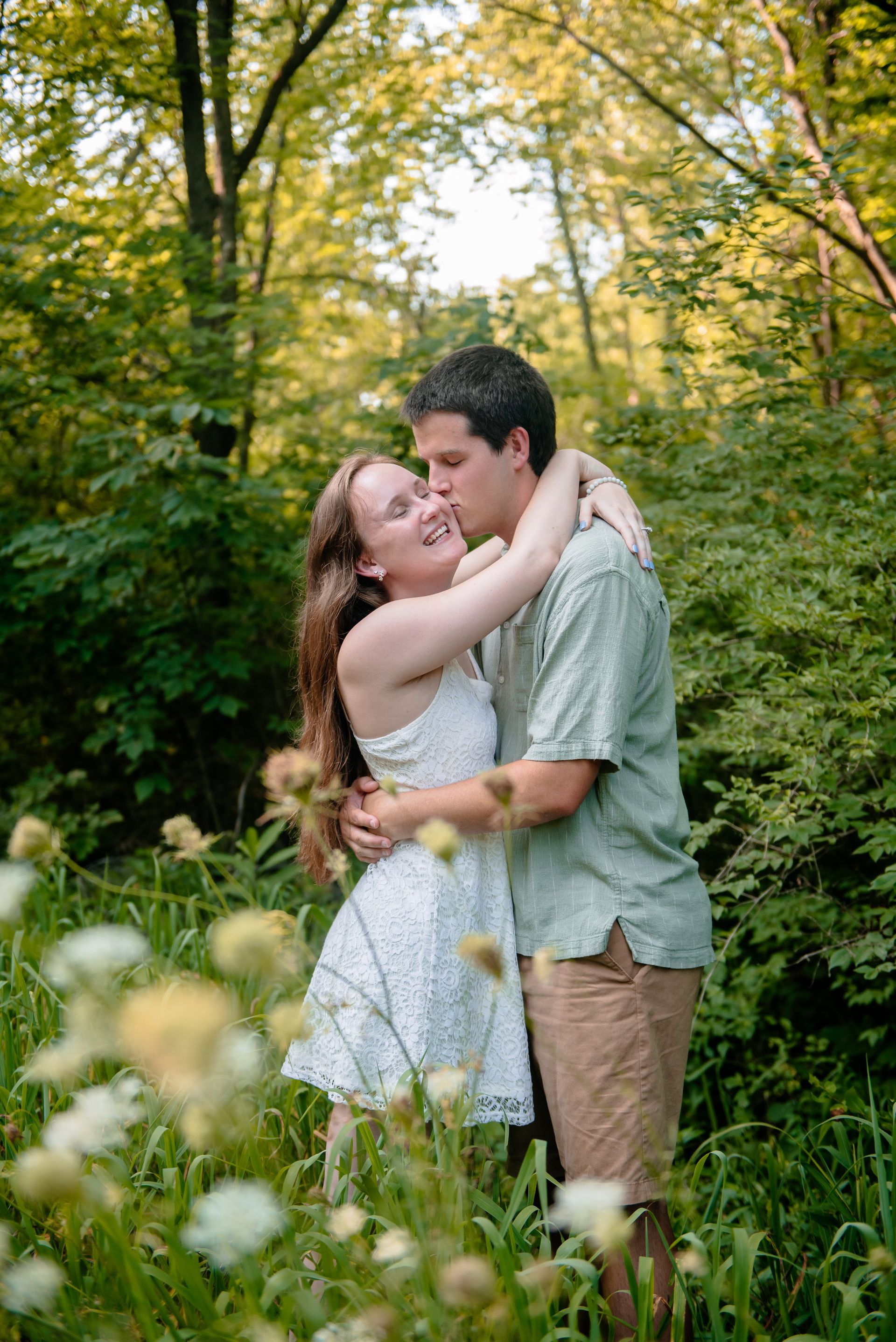 A man and a woman are hugging in a field of flowers.