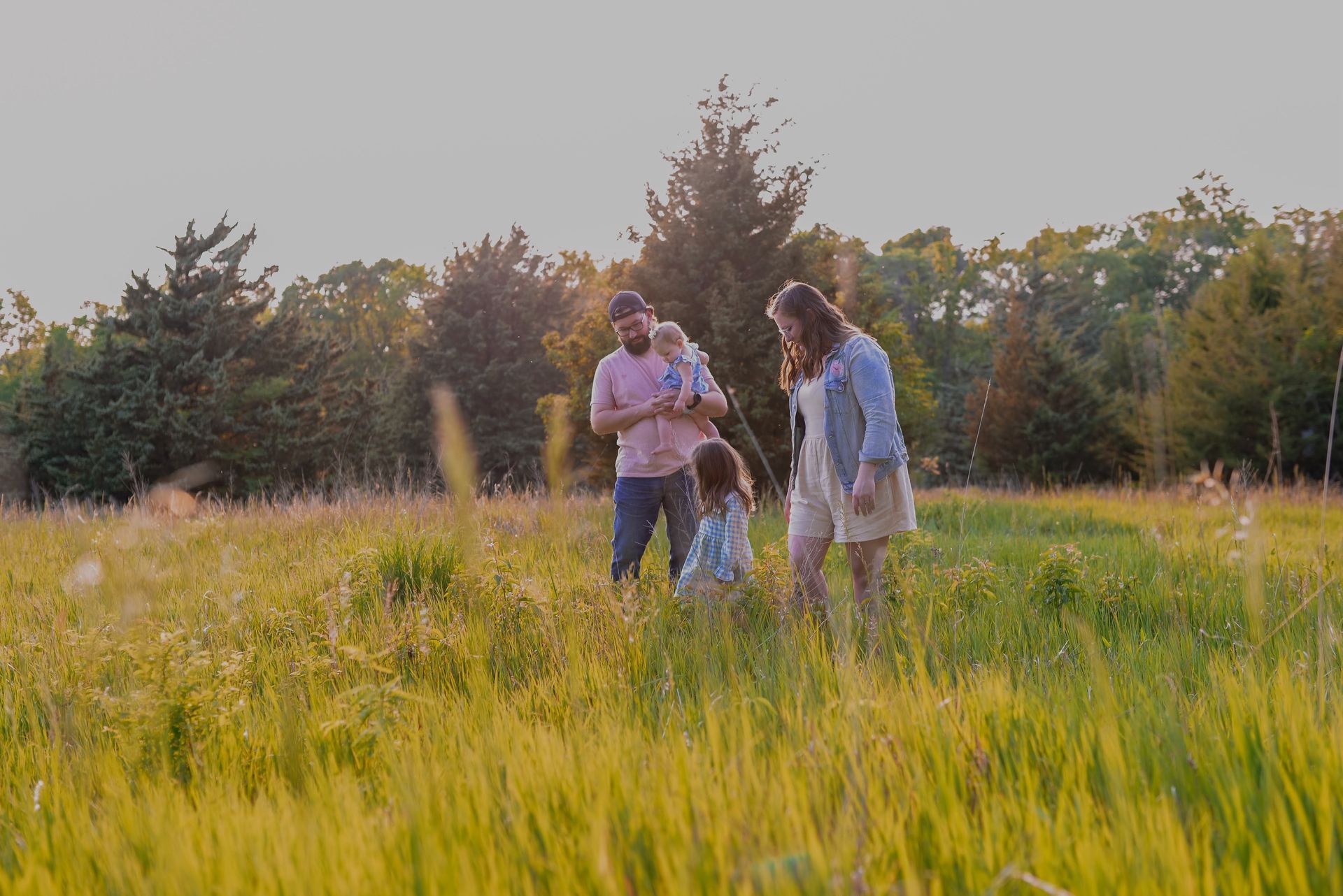 A family is walking through a field of tall grass.