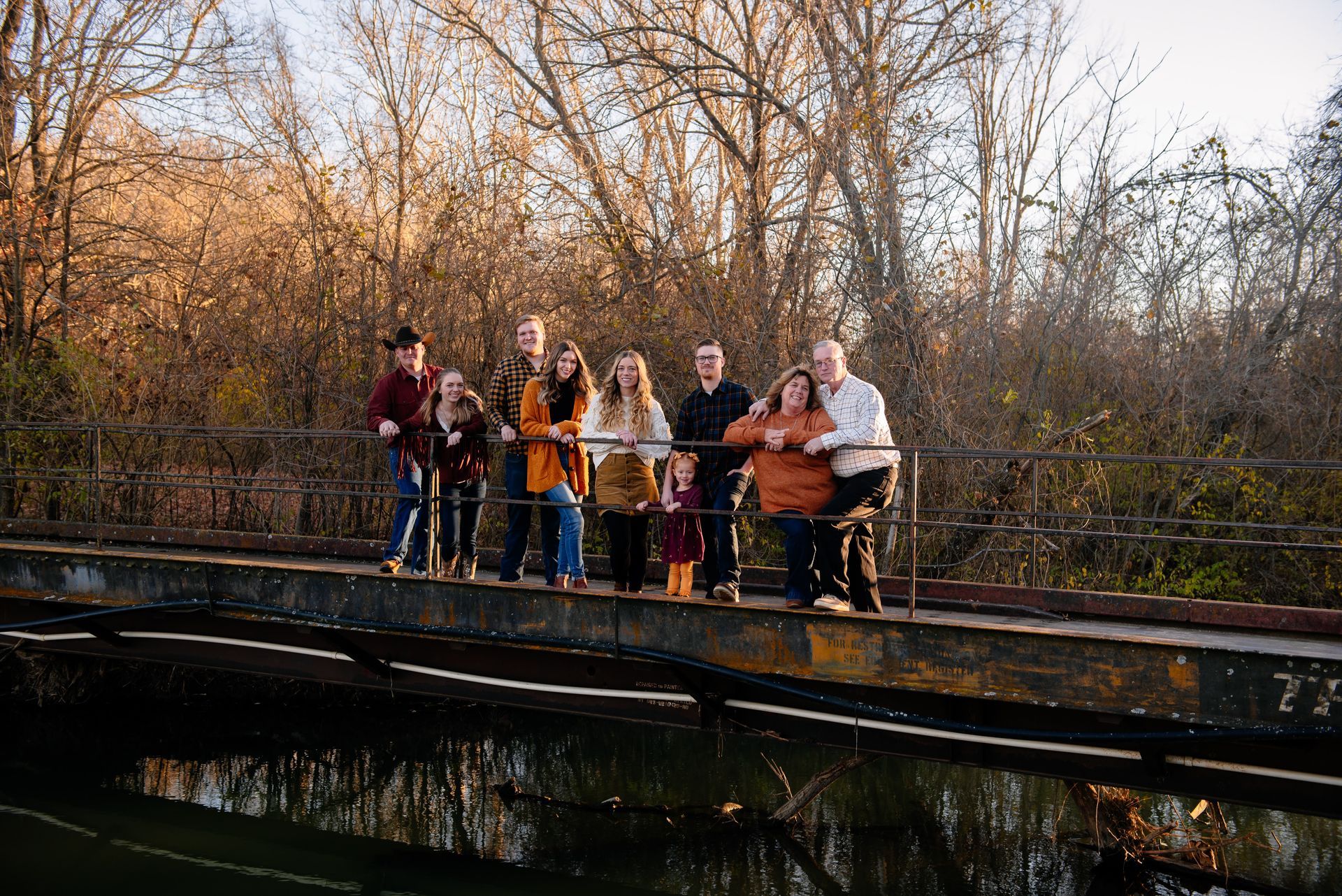 A large family is standing on a bridge over a river.