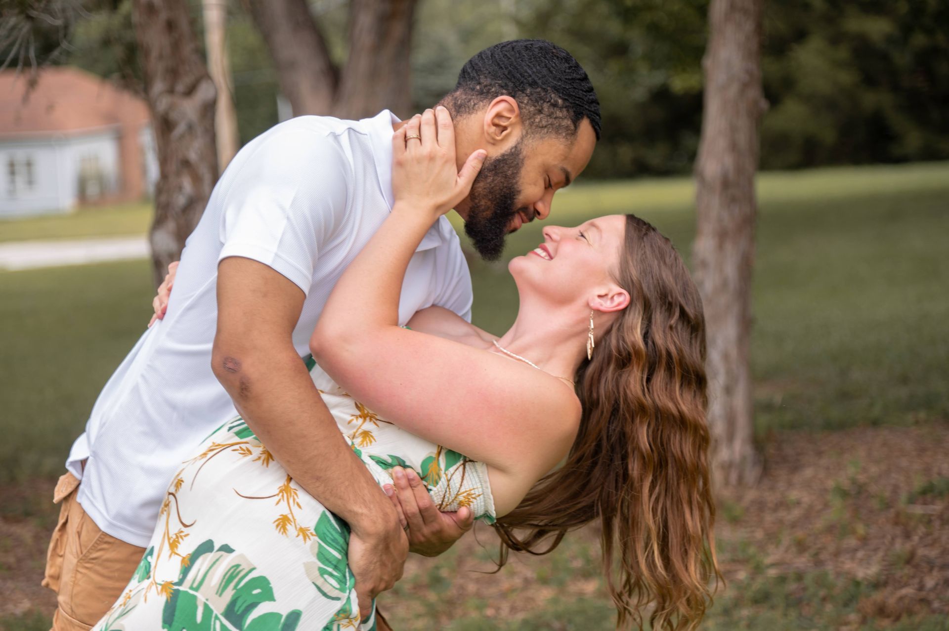 A man is holding a woman in his arms in a park.