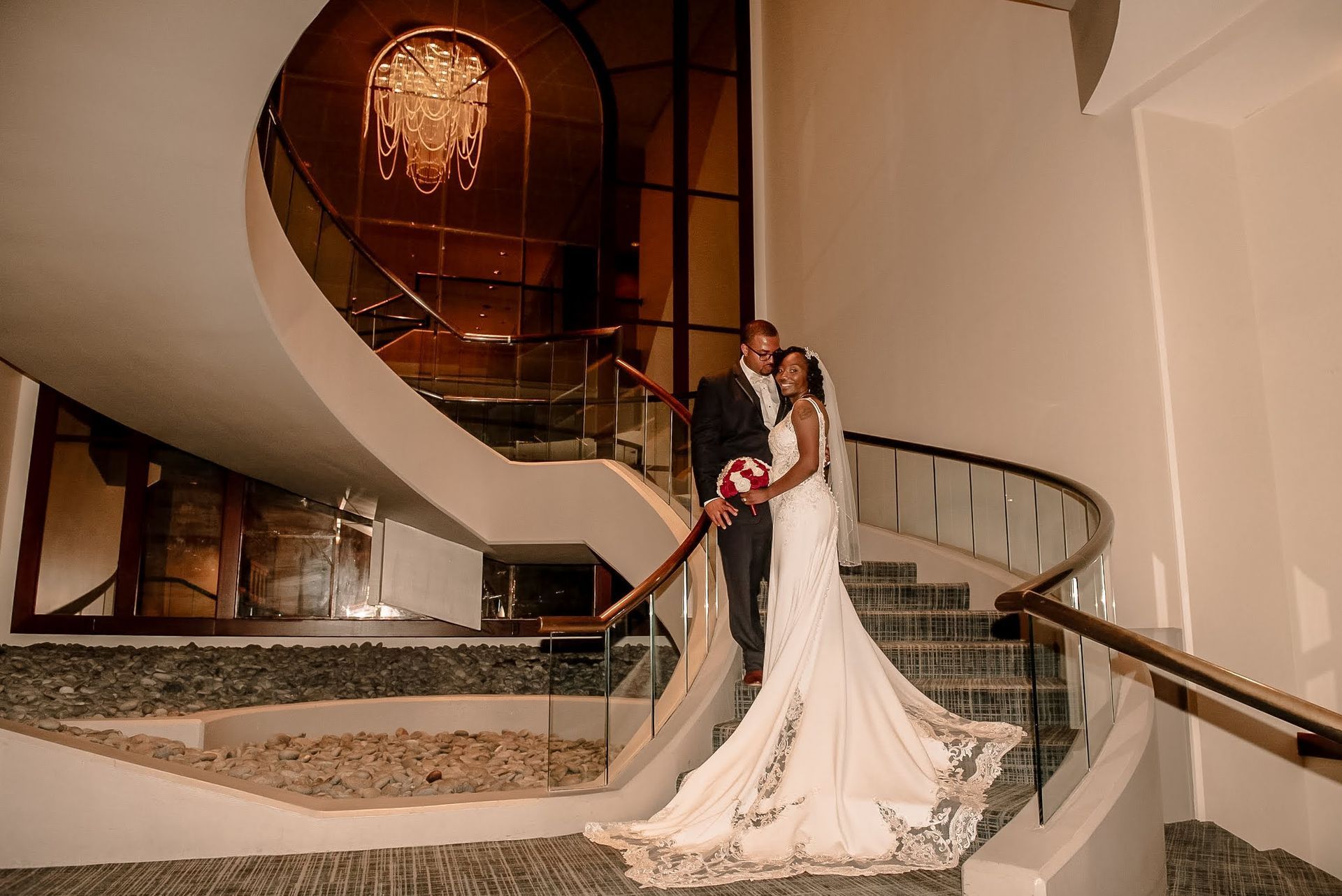 A bride and groom are posing for a picture on a spiral staircase.