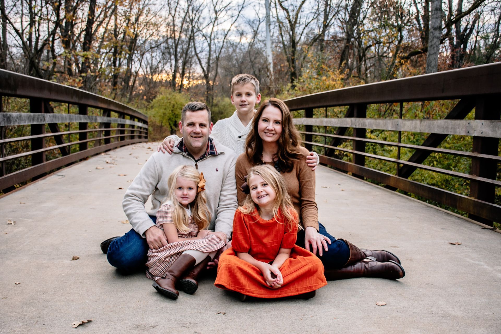 A family is posing for a picture on a bridge.
