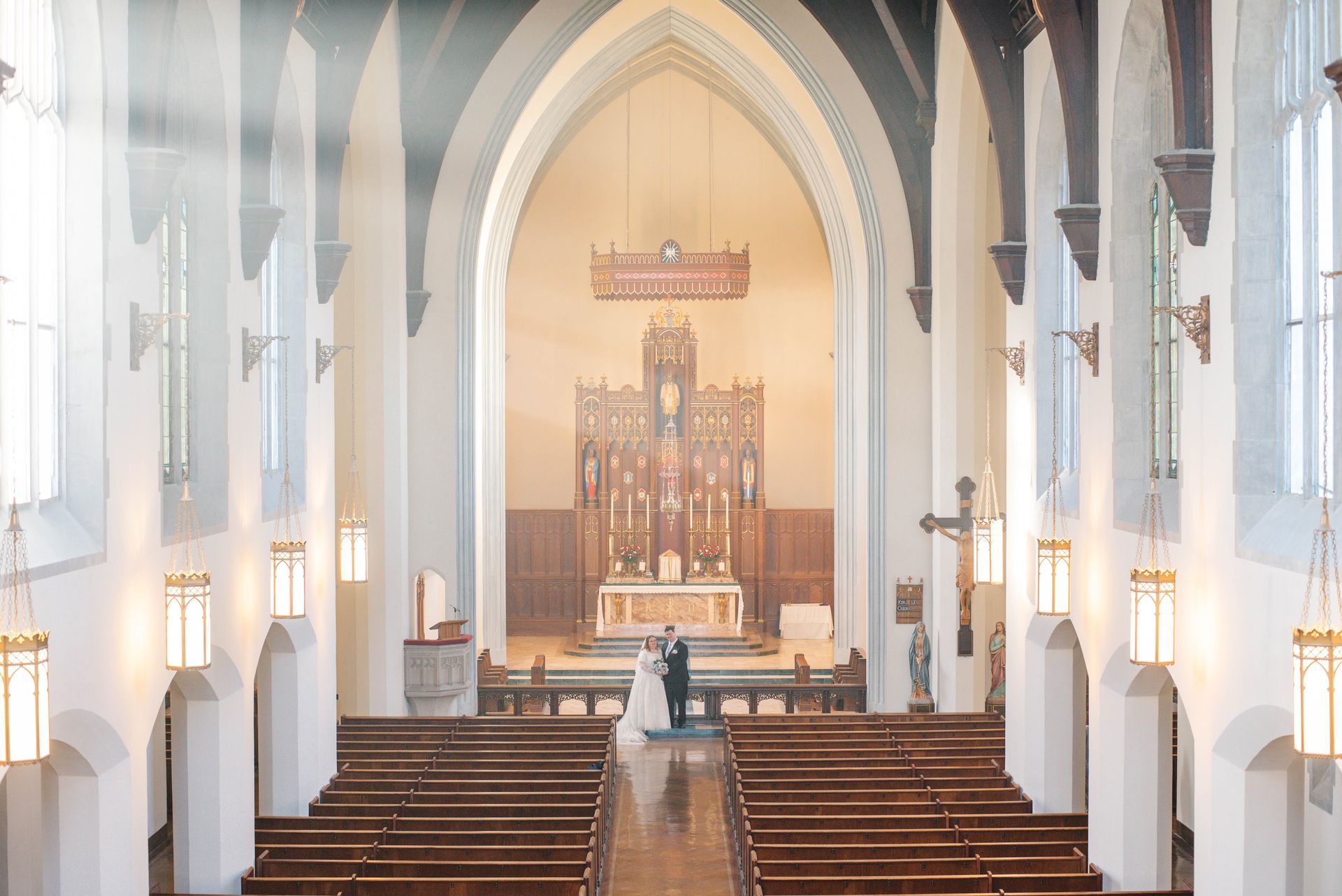 A bride and groom are standing in the middle of a church.