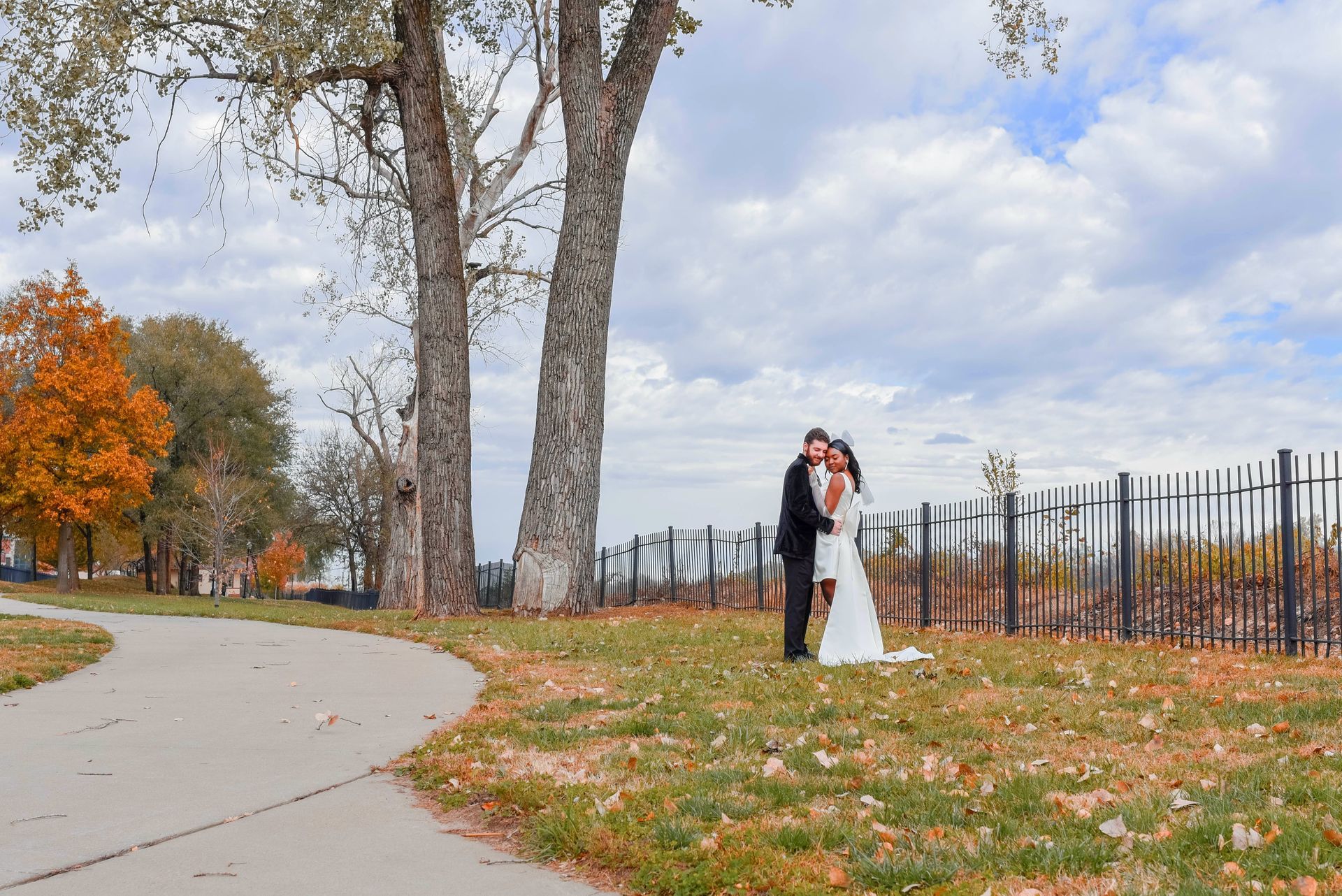 A bride and groom are kissing in a park.