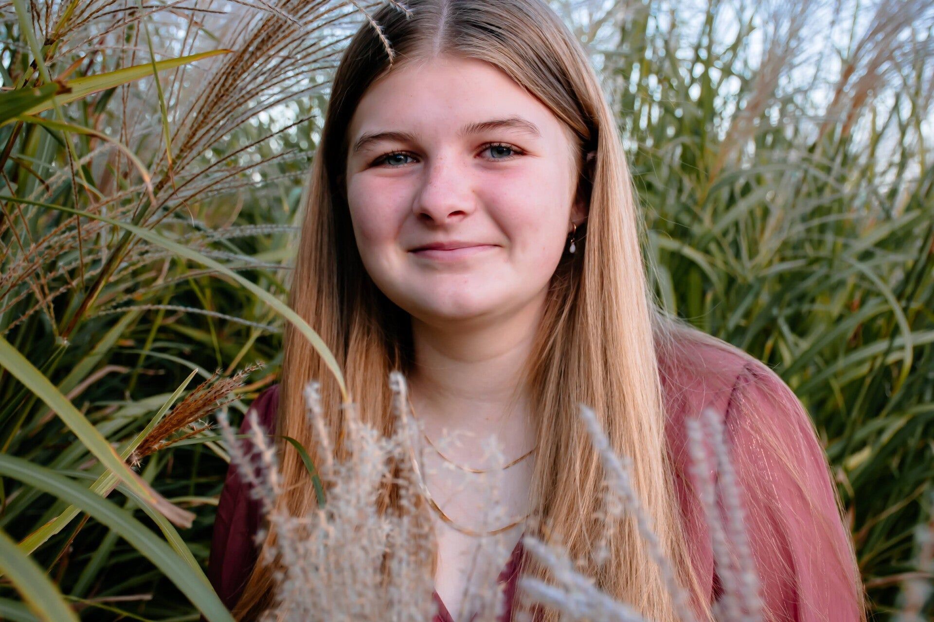 A young woman is standing in a field of tall grass.