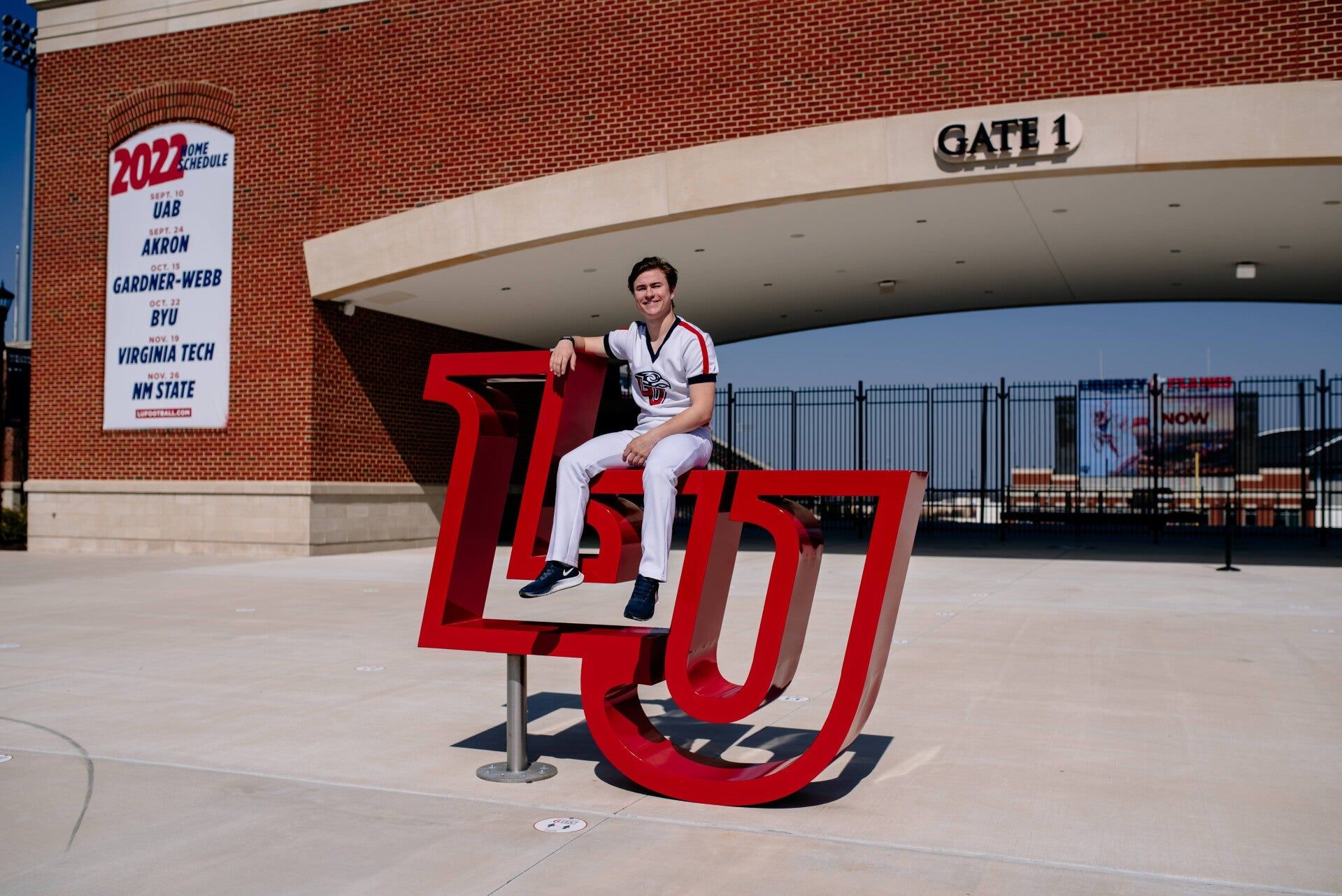 A baseball player is sitting on a statue of the letter l and j.