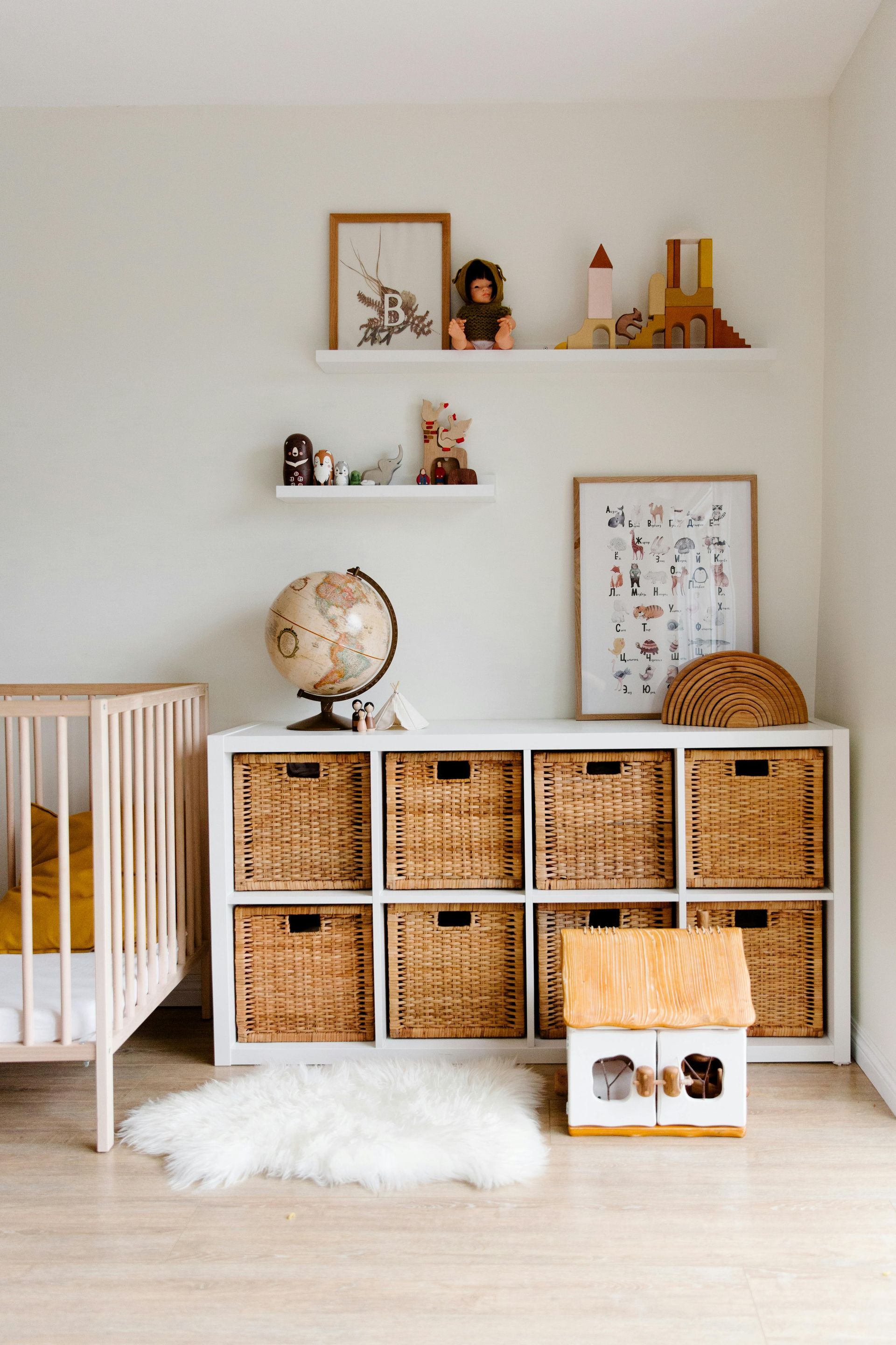 A nursery with a crib , wicker baskets , a globe , and shelves.