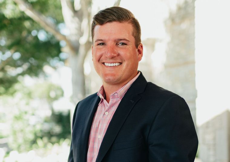 A man in a suit and pink shirt is smiling for the camera.