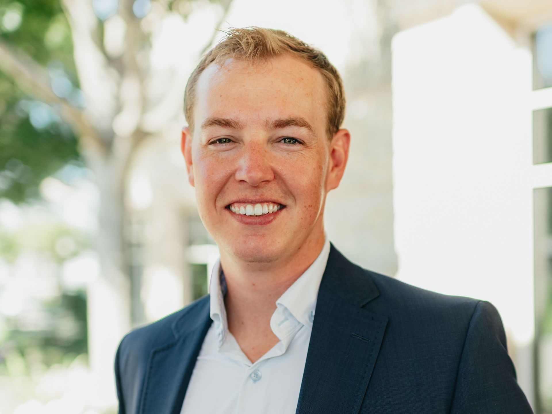 A man in a suit and white shirt is smiling for the camera.