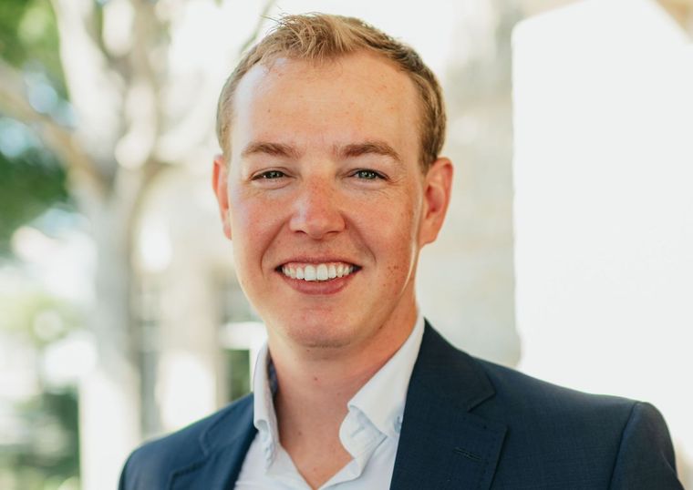 A man in a suit and white shirt is smiling for the camera.