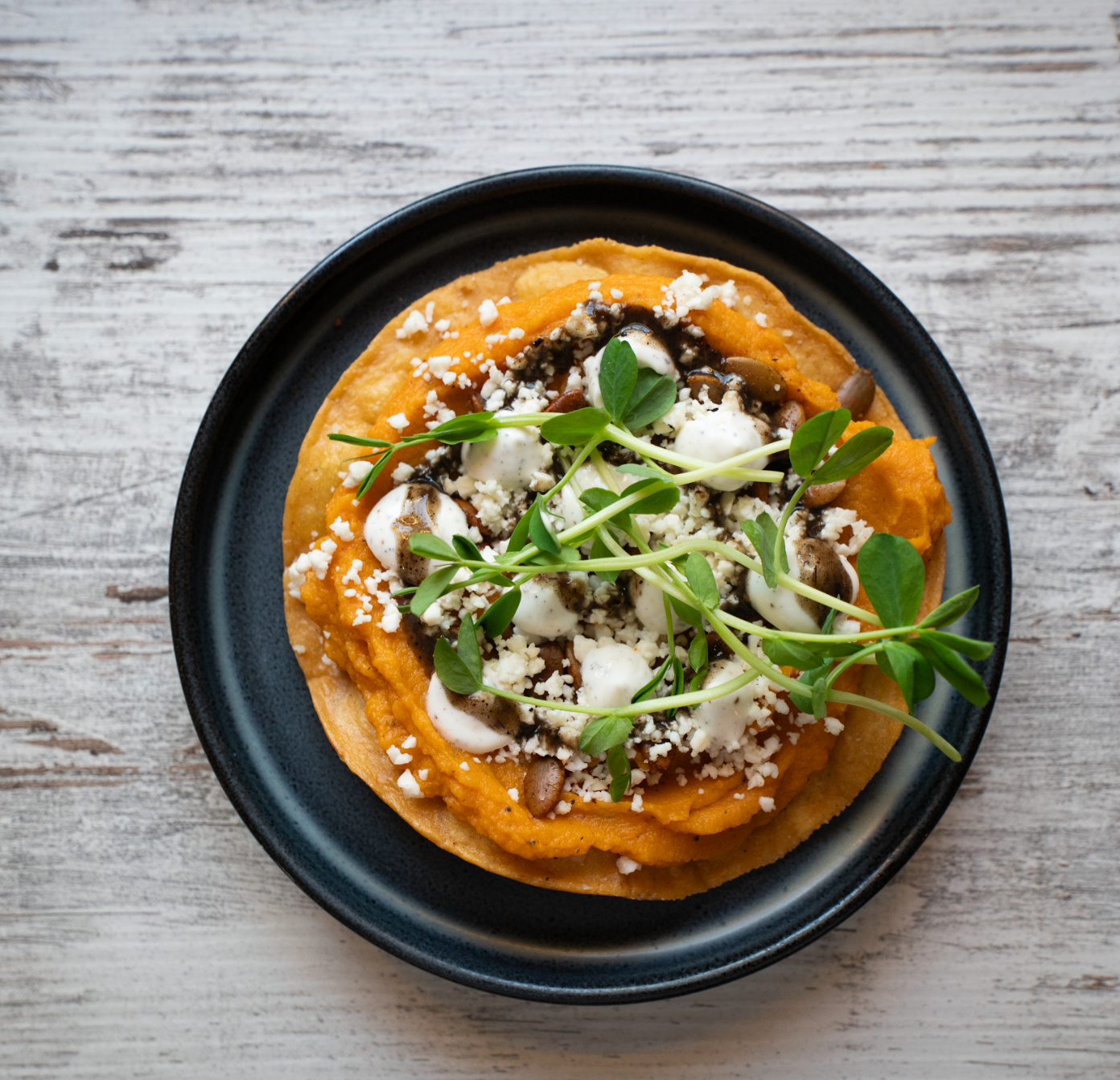 A pizza on a black plate on a wooden table
