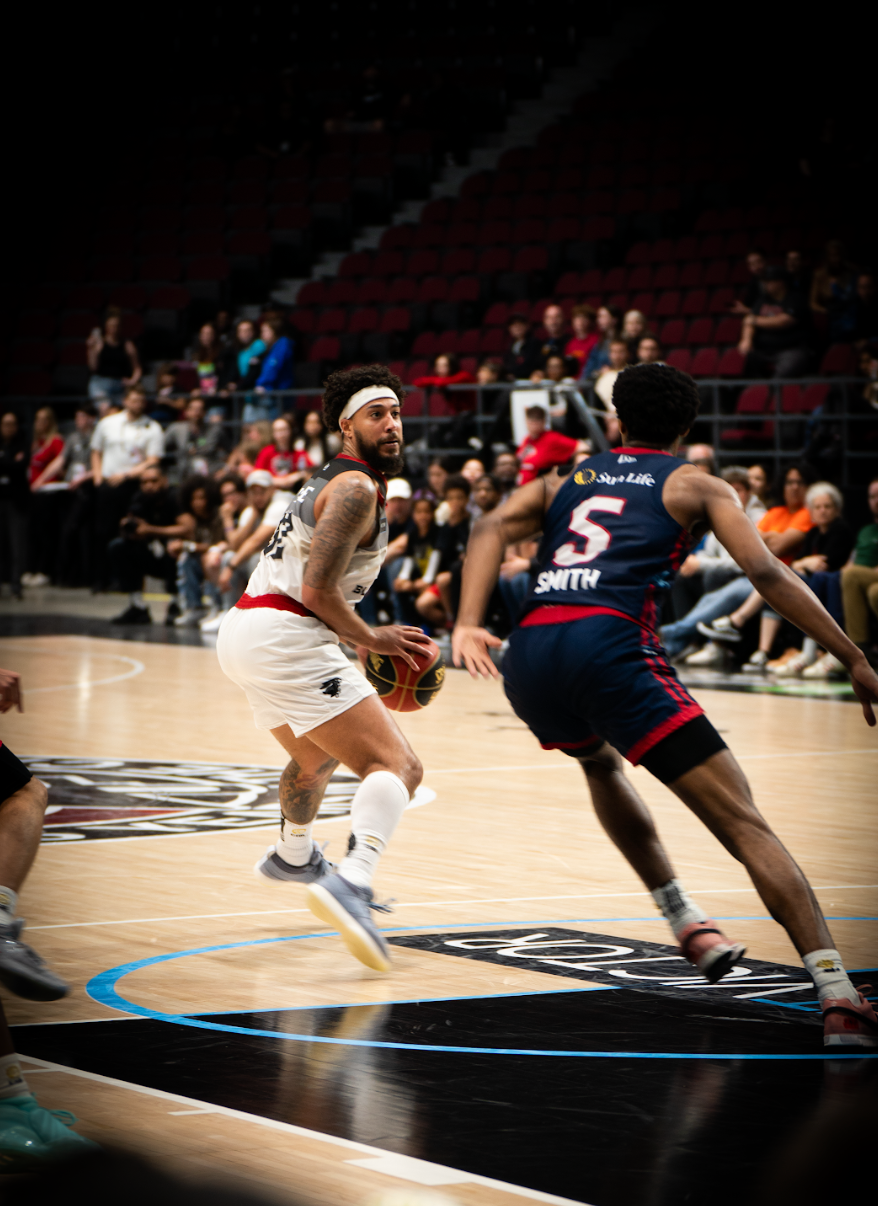 Two basketball players are playing a game of basketball on a court.