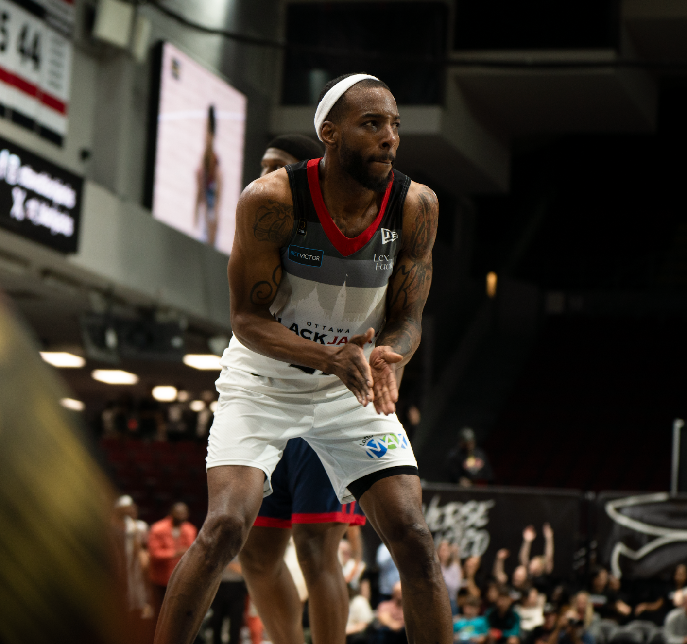 A man is playing basketball in front of a crowd in a stadium.