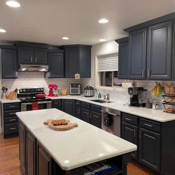 A kitchen with gray cabinets and white counter tops