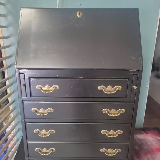 A black dresser with gold handles and a lock