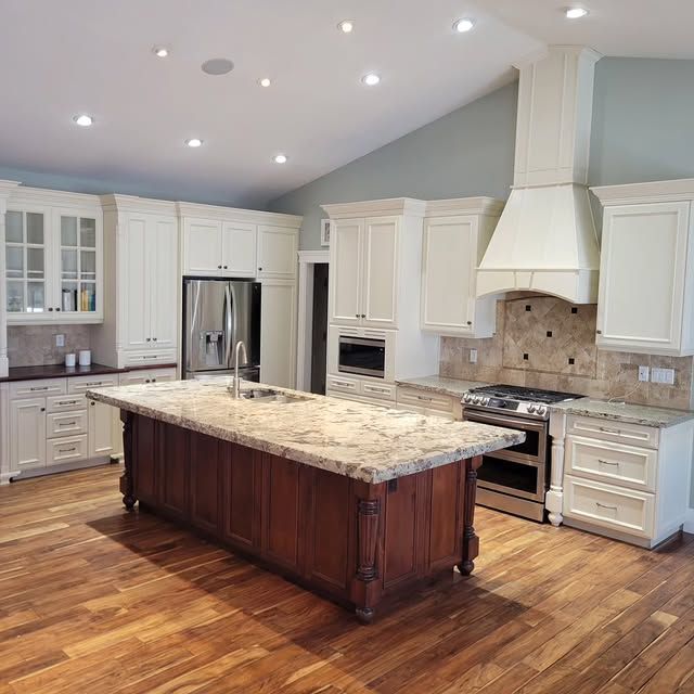 A kitchen with white cabinets and a large island in the middle