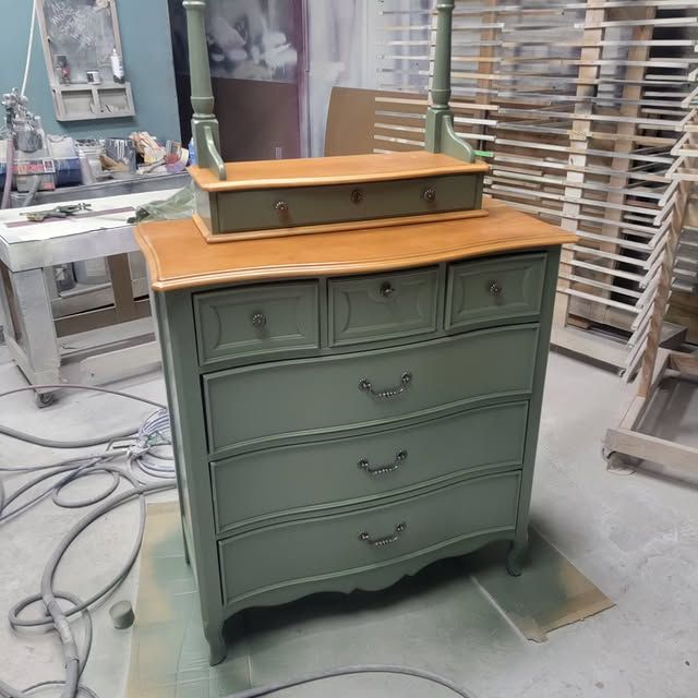 A green dresser with four drawers and a mirror on top
