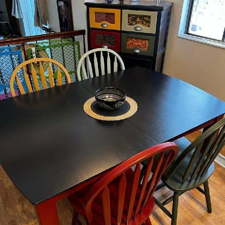 A black table with red chairs and a bowl on it