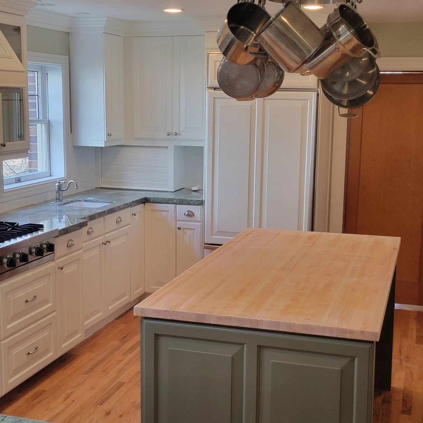 A kitchen with pots and pans hanging from the ceiling