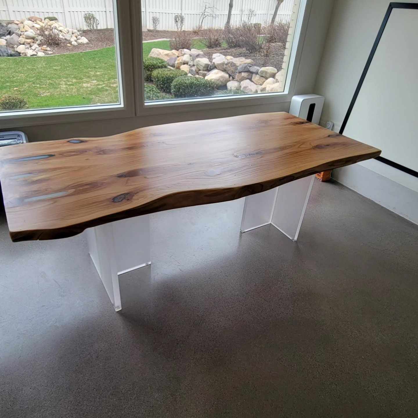 A wooden table is sitting in a room next to a window.