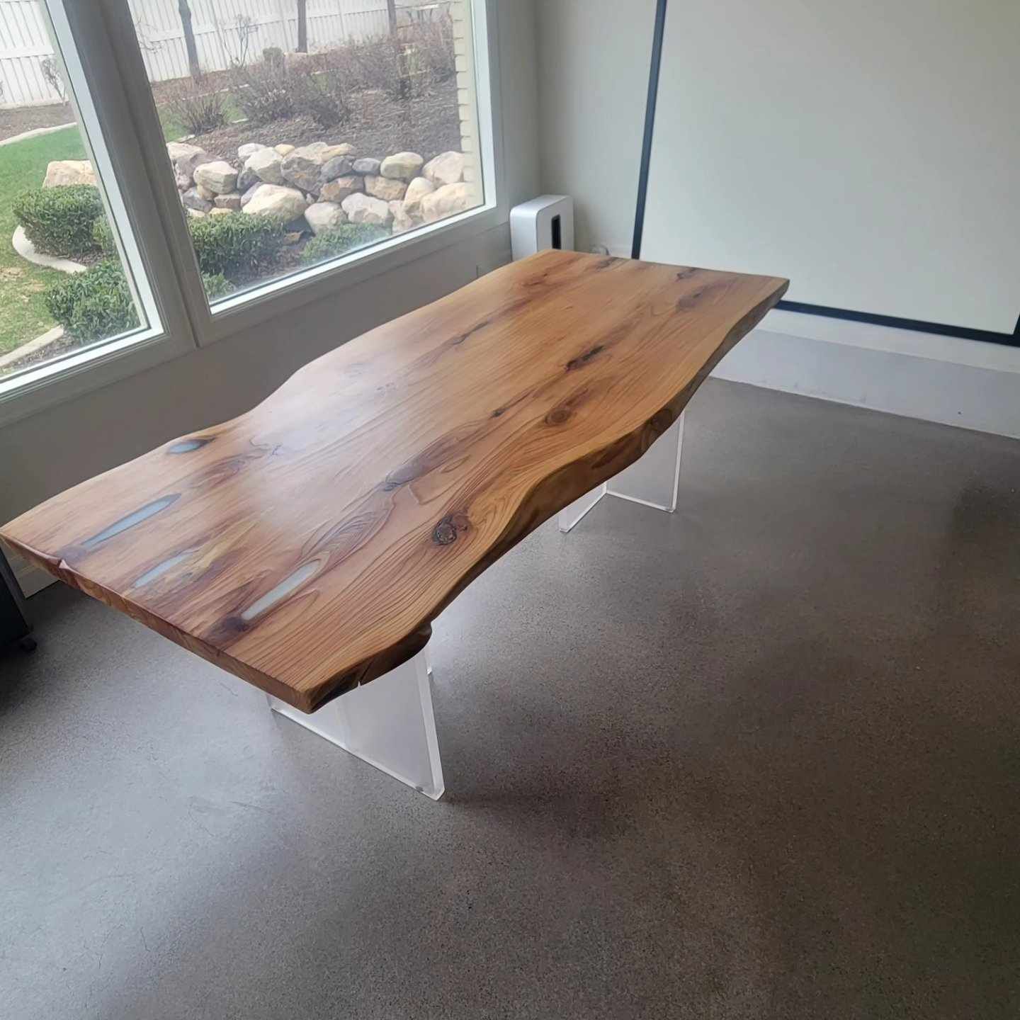 A wooden table is sitting in a room next to a window.