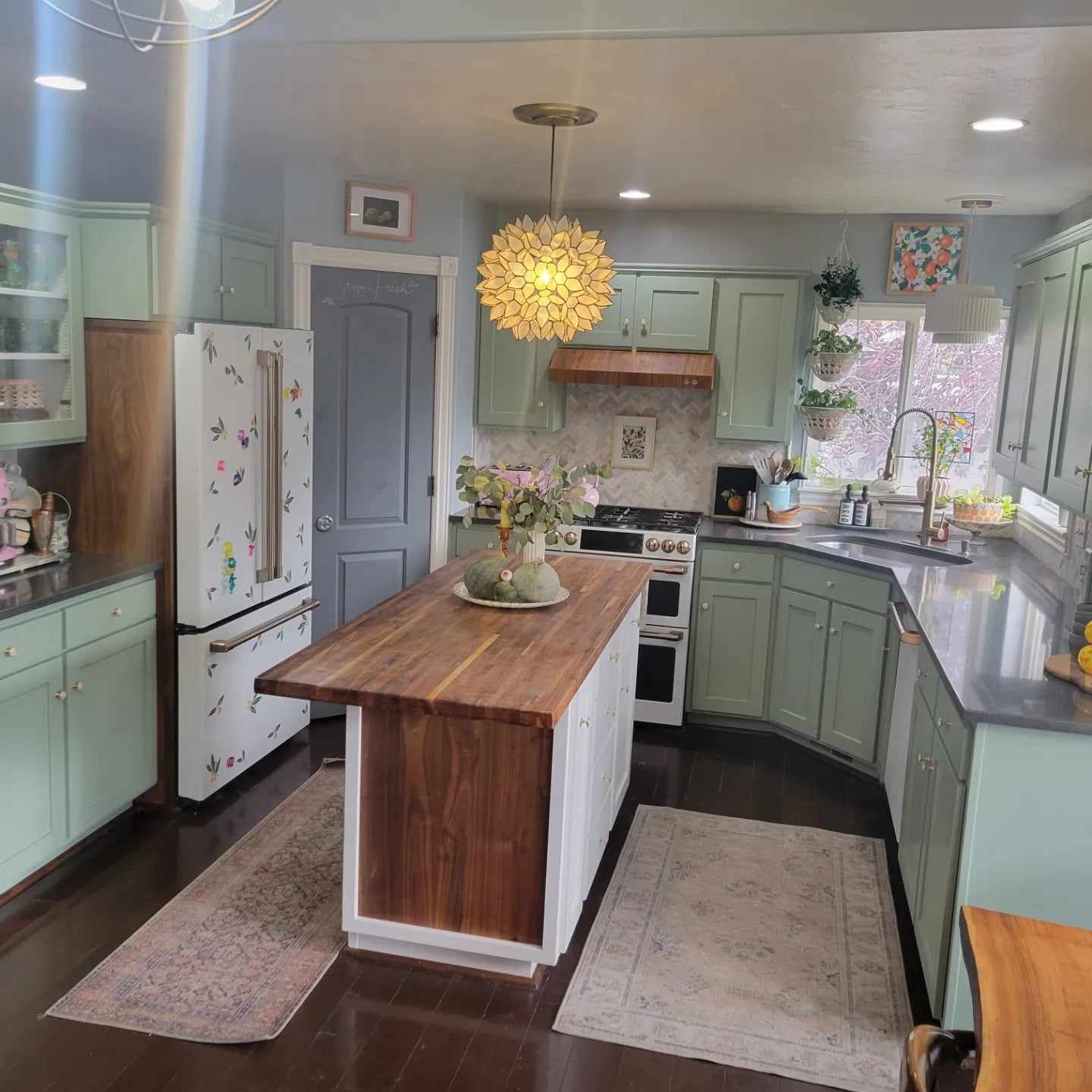 A kitchen with green cabinets and a large wooden island