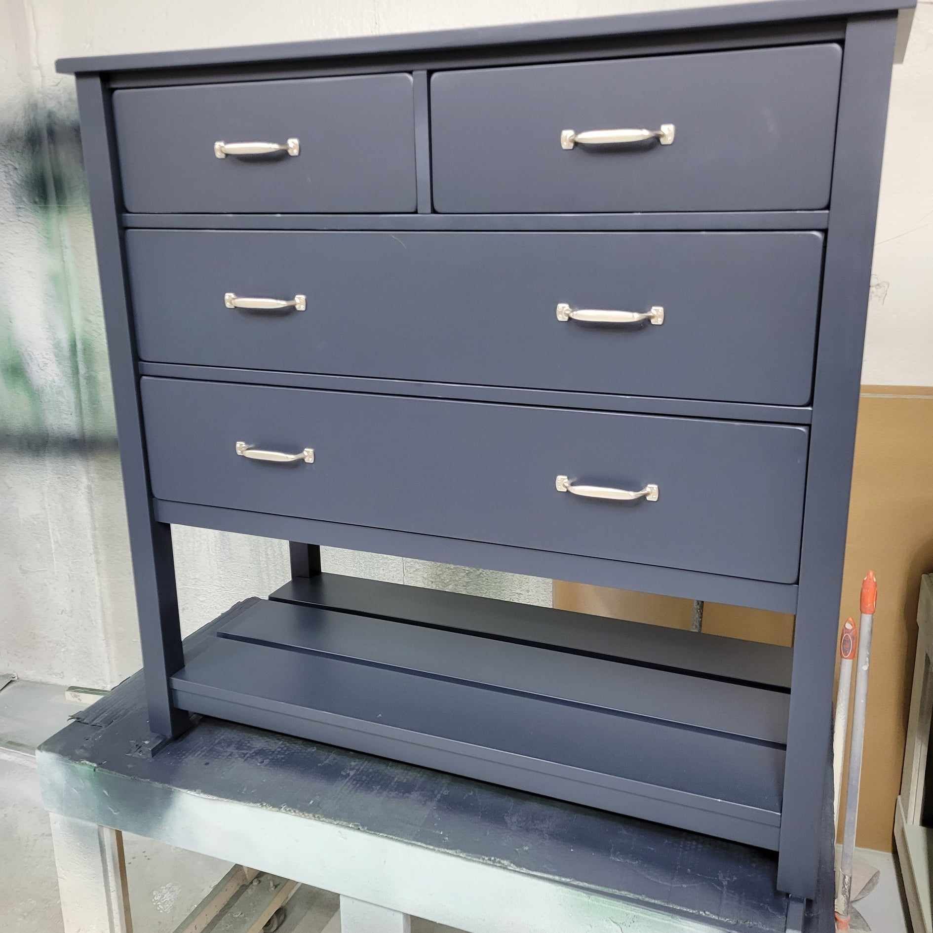 A blue dresser with four drawers and a shelf