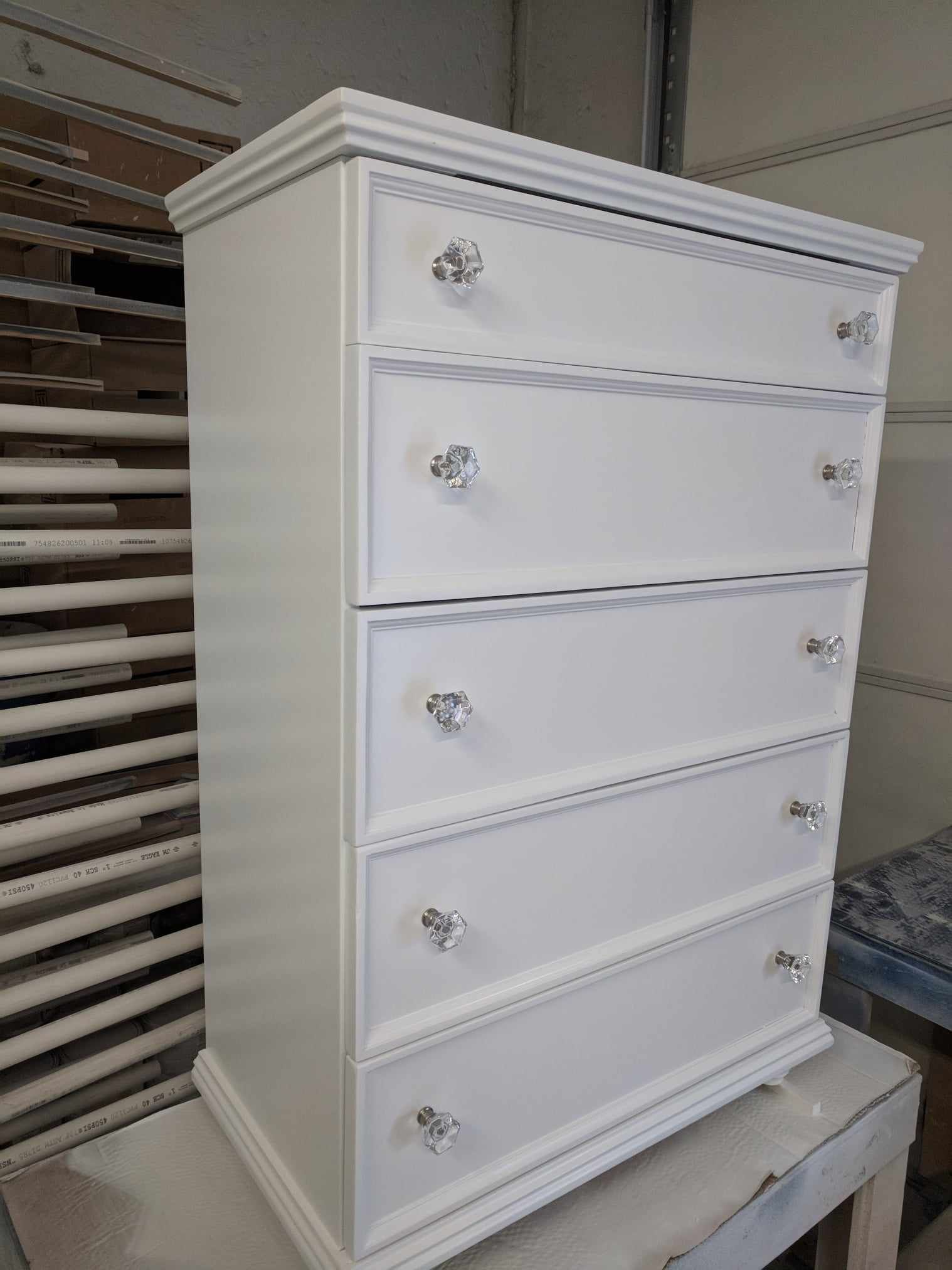 A white chest of drawers is sitting on top of a table.