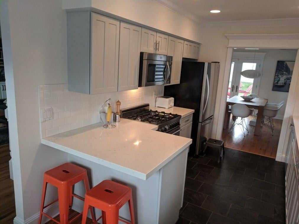 A kitchen with white cabinets and orange stools