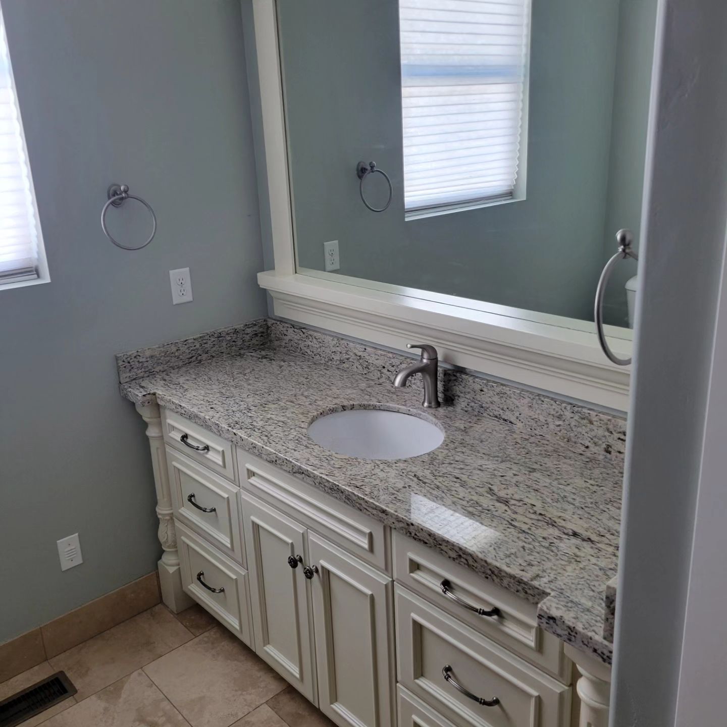 Bathroom with a white vanity, granite countertop, oval sink, and large mirror.