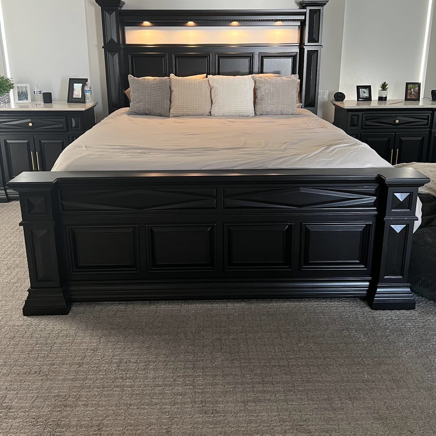 Black bedroom set with bed, nightstands, and headboard with built-in lights.