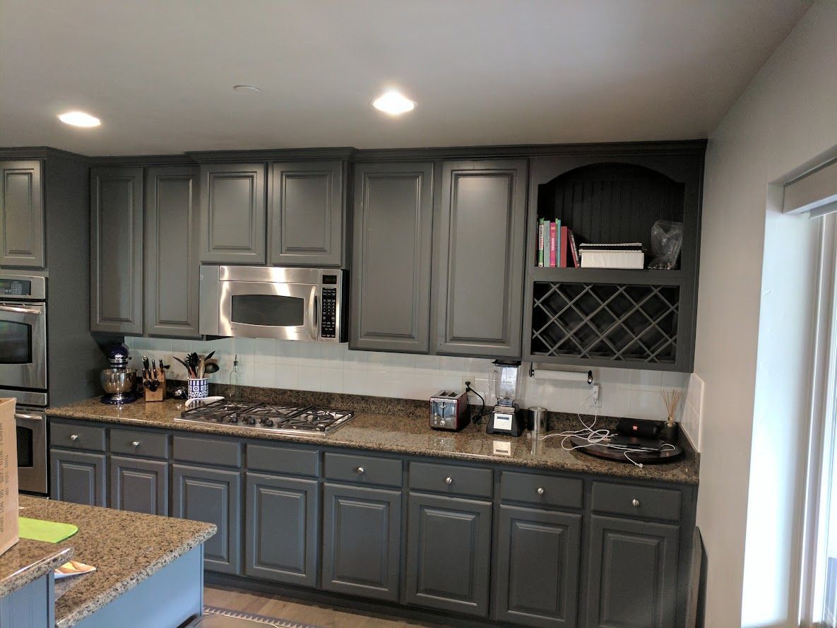 A kitchen with gray cabinets and granite counter tops