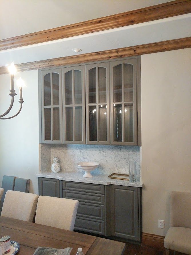 A dining room with a table and chairs and gray cabinets