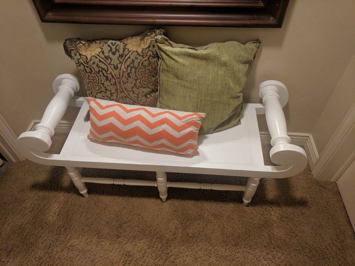 A white bench with pillows on it in a hallway.