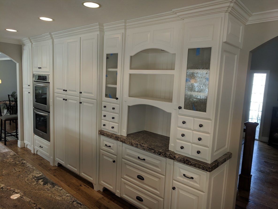 A kitchen with white cabinets and granite counter tops.