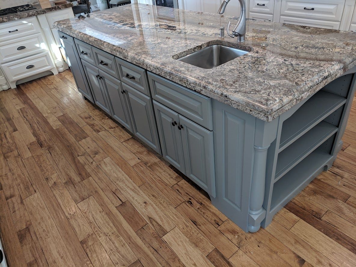 A kitchen island with a sink and granite counter tops.