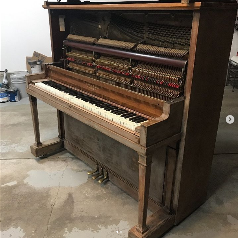 A piano is sitting on the floor in a garage