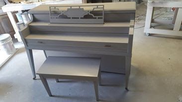 A piano with a bench underneath it is sitting on the floor in a room.