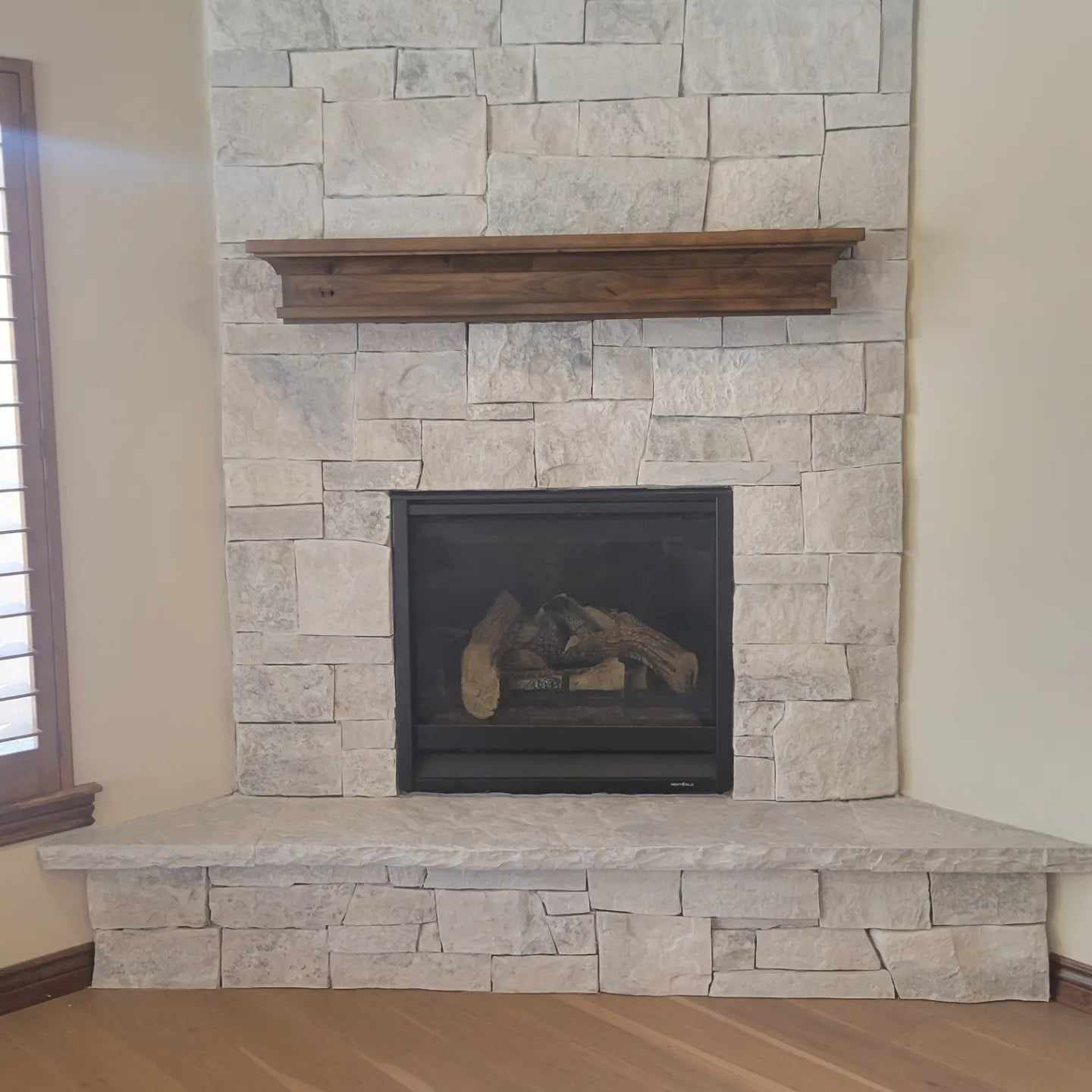 A stone fireplace with a wooden mantle in a living room.