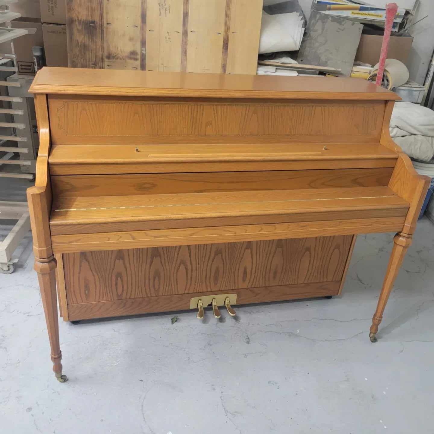 A wooden piano is sitting on the floor in a room.