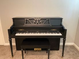 A black piano with a bench is sitting in a room.