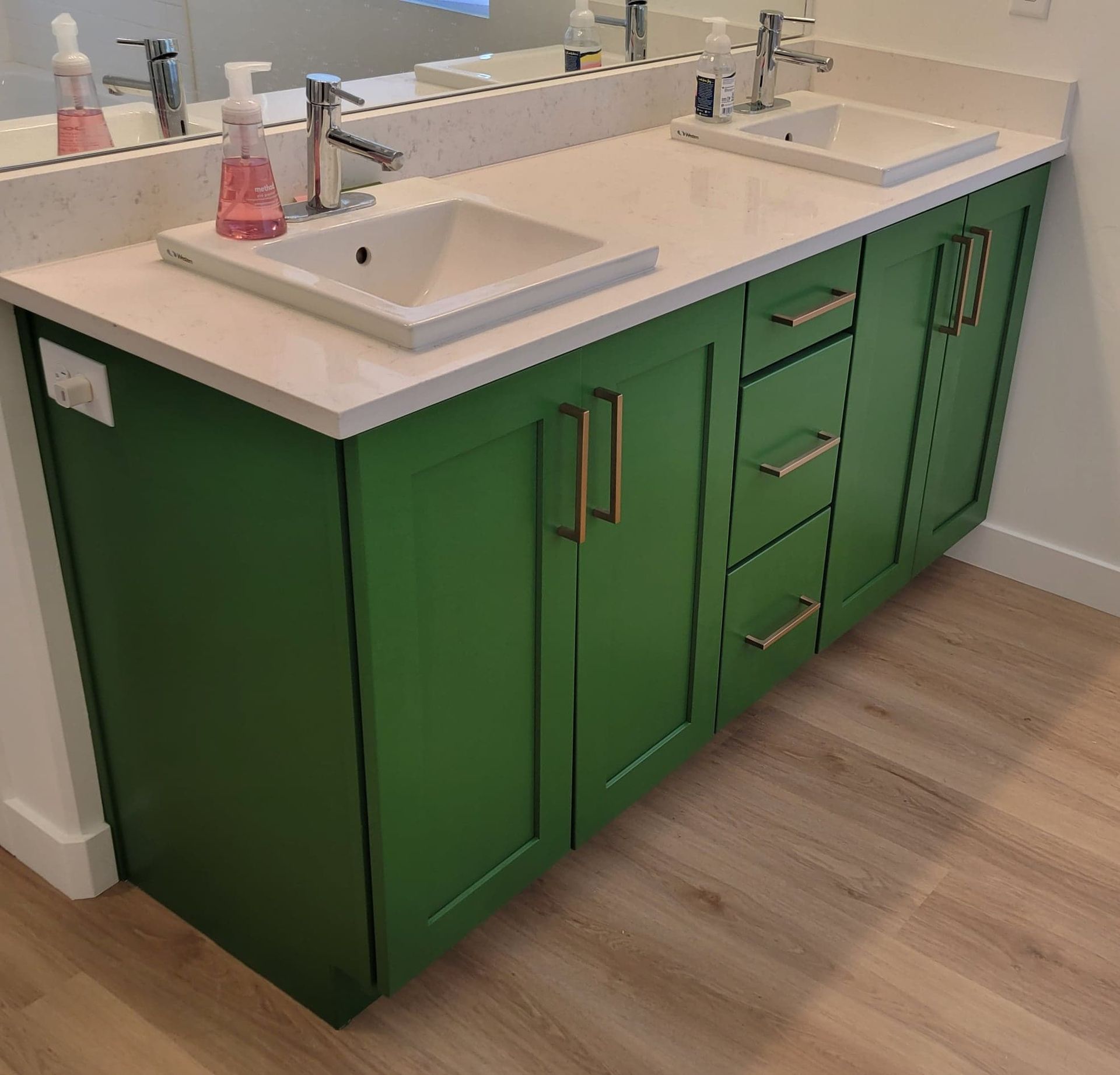 A bathroom vanity with green cabinets and two sinks