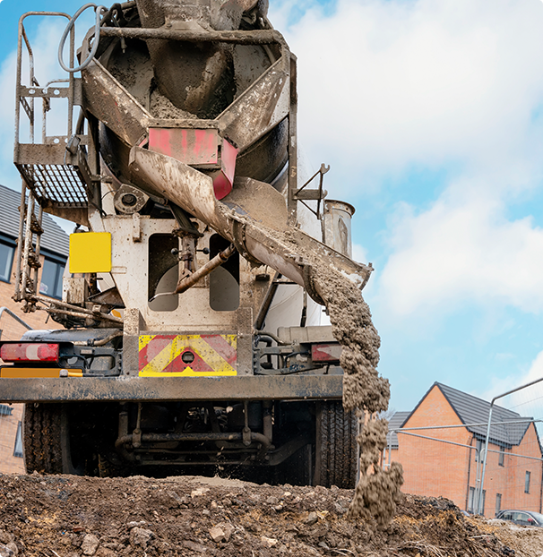 A concrete mixer truck is pouring concrete into a pile of dirt.